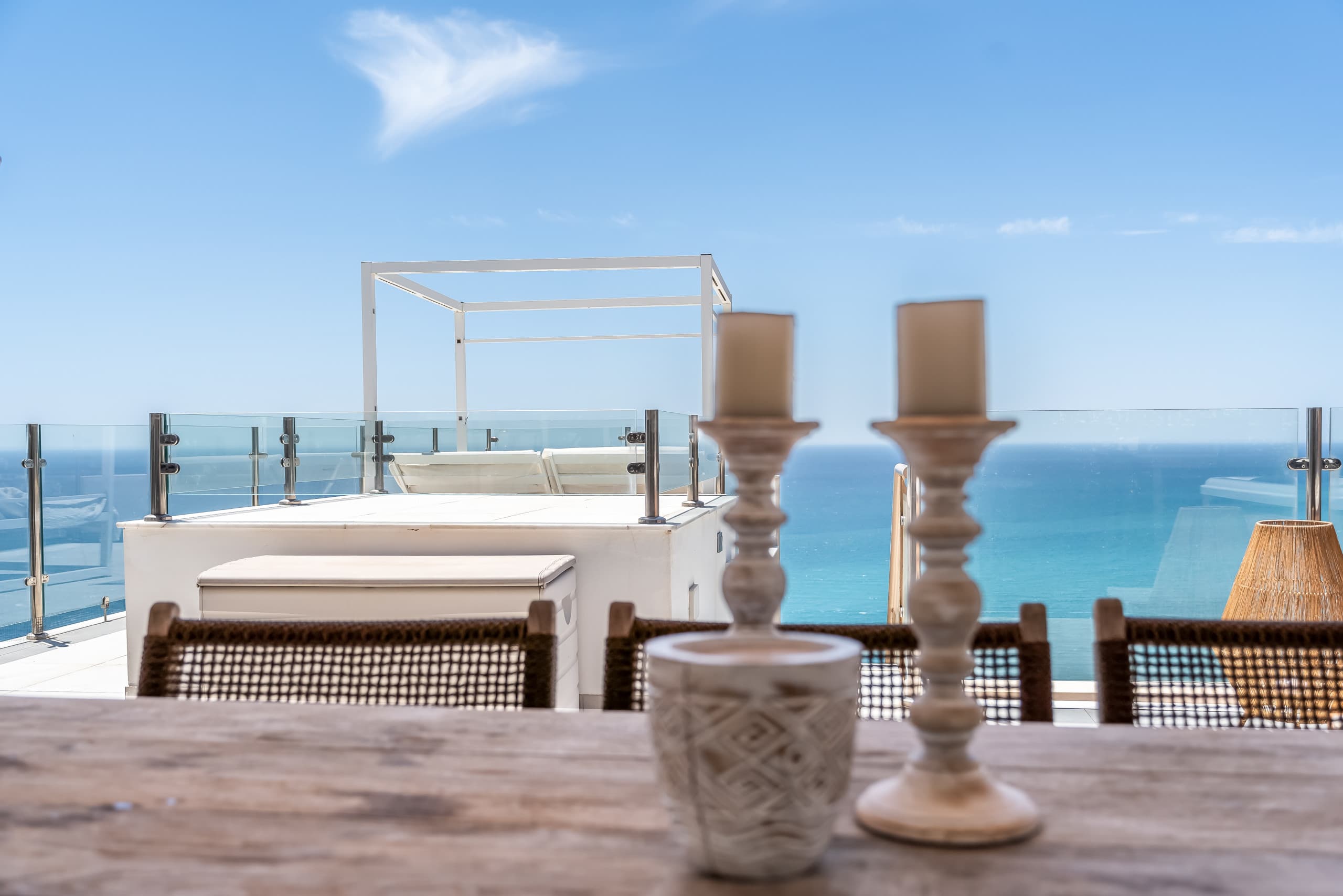 Candle vignette with rooftop daybed and sea in background